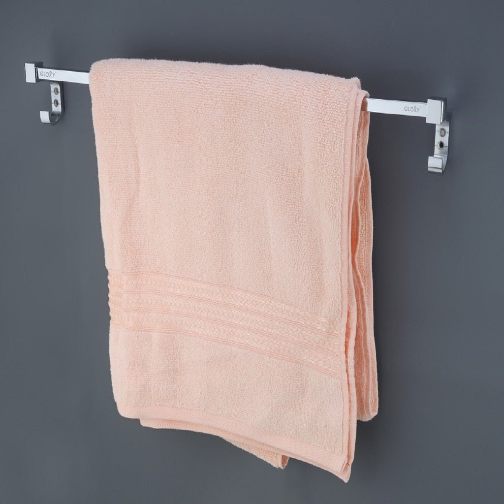 a stainless steel towel rod with a nickel-chrome plating and a pink towel hanging on mounted on a gray wall.