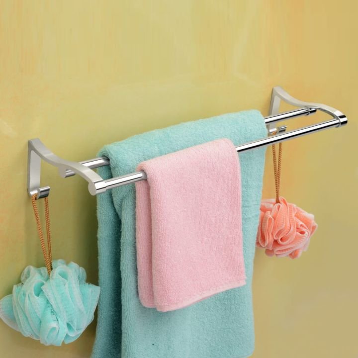 A stainless steel towel rod with a towel hanging on it, mounted on a yellow wall.