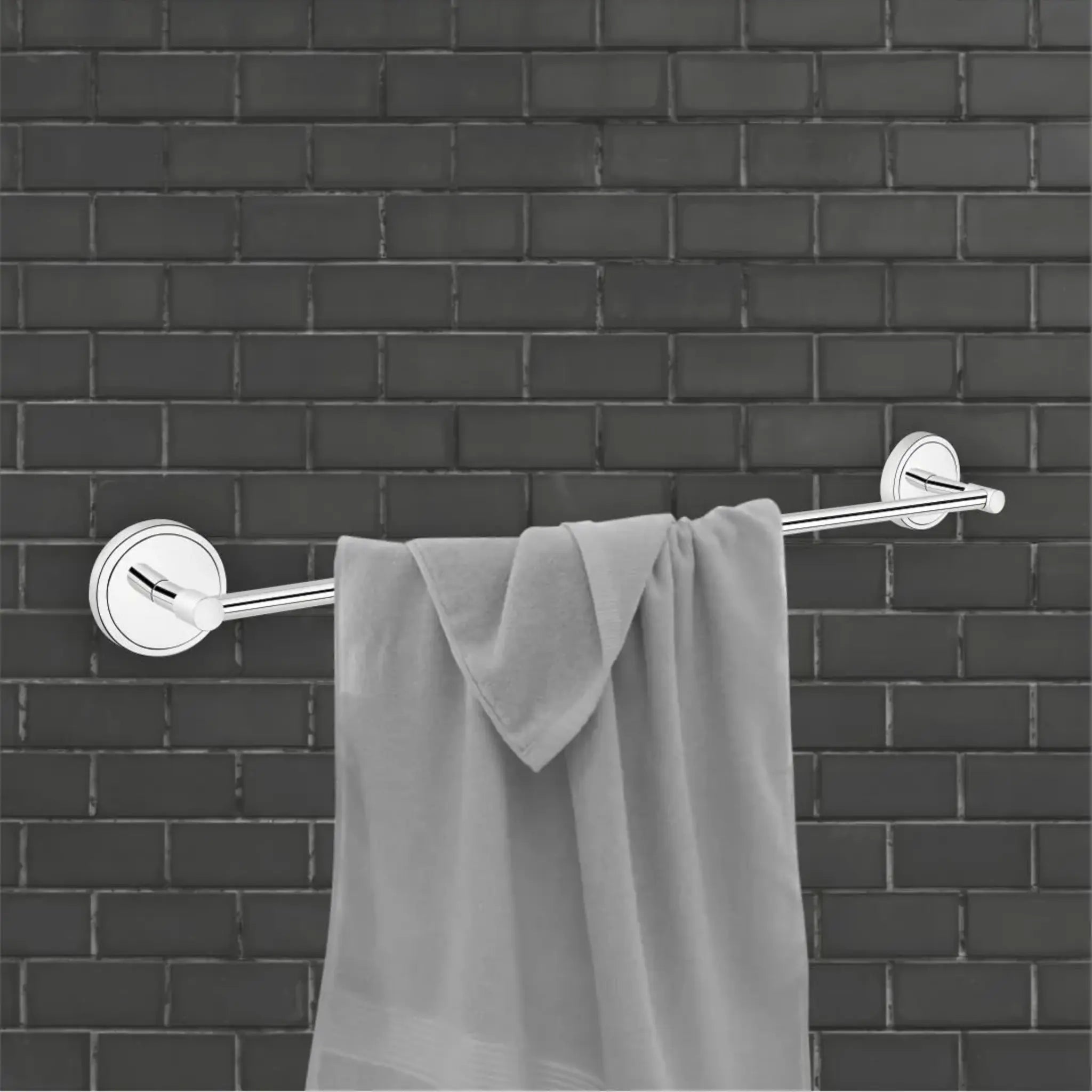 Gray towel hanging on a silver towel rack against a black brick wall.