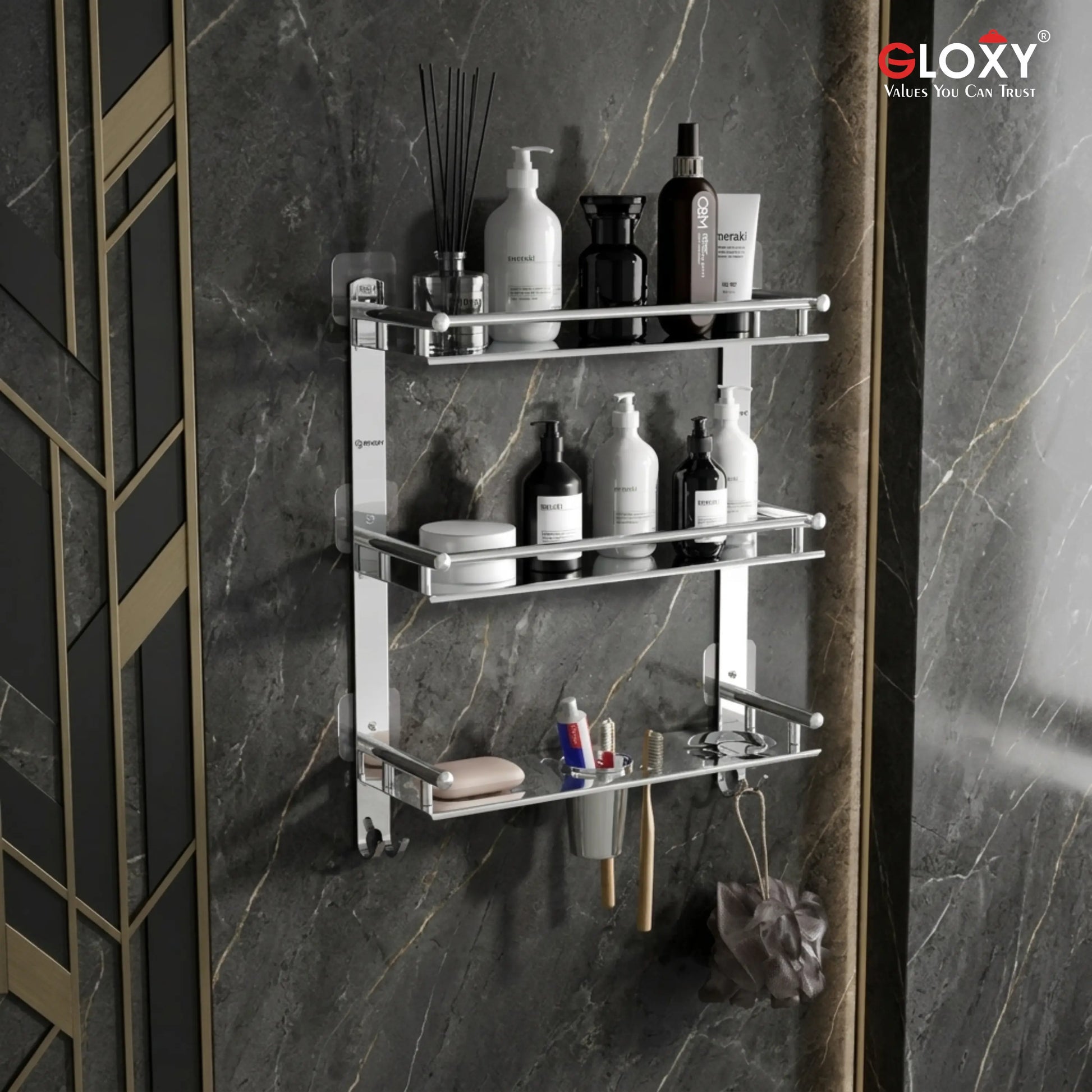 A wall-mounted three-tier chrome bathroom shelf with bottles, jars, and toiletries displayed on a dark marble wall. The brand logo 'eLOXY' is visible in the top right corner.